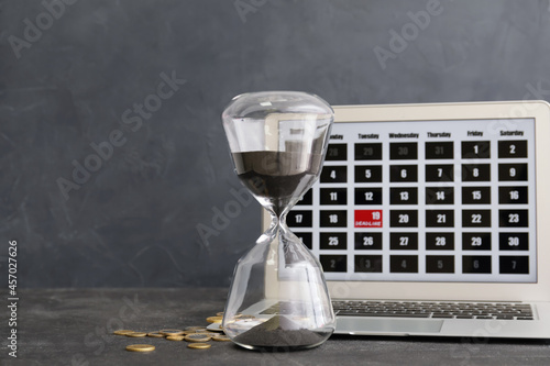 Hourglass and laptop on dar...