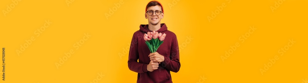 handsome man with a bouquet of flowers, a man in an orange hat and a red sweater holding flowers in his hands handsome man with a bouquet of flowers, a man in an orange hat and a red sweater holding flowers in his hands