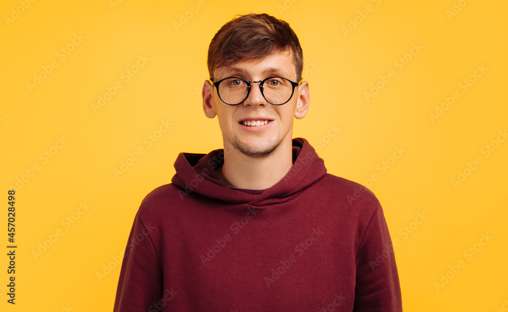 portrait of a handsome man in glasses and a red sweatshirt, in the studio on a yellow background