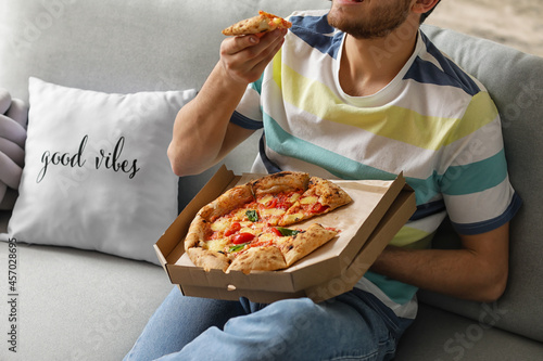Young man eating tasty pizz...