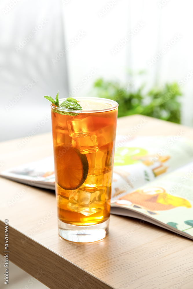 Glass of tasty ice tea with lemon on table in room Glass of tasty ice tea with lemon on table in room