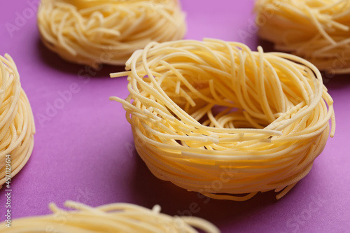 Uncooked birds nest pasta on color background