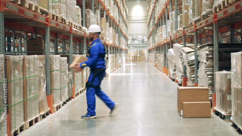 Male employee is wearing ergoskeleton while transporting boxes Male employee is wearing ergoskeleton while transporting boxes