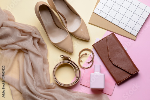 Stylish female accessories and shoes on color background