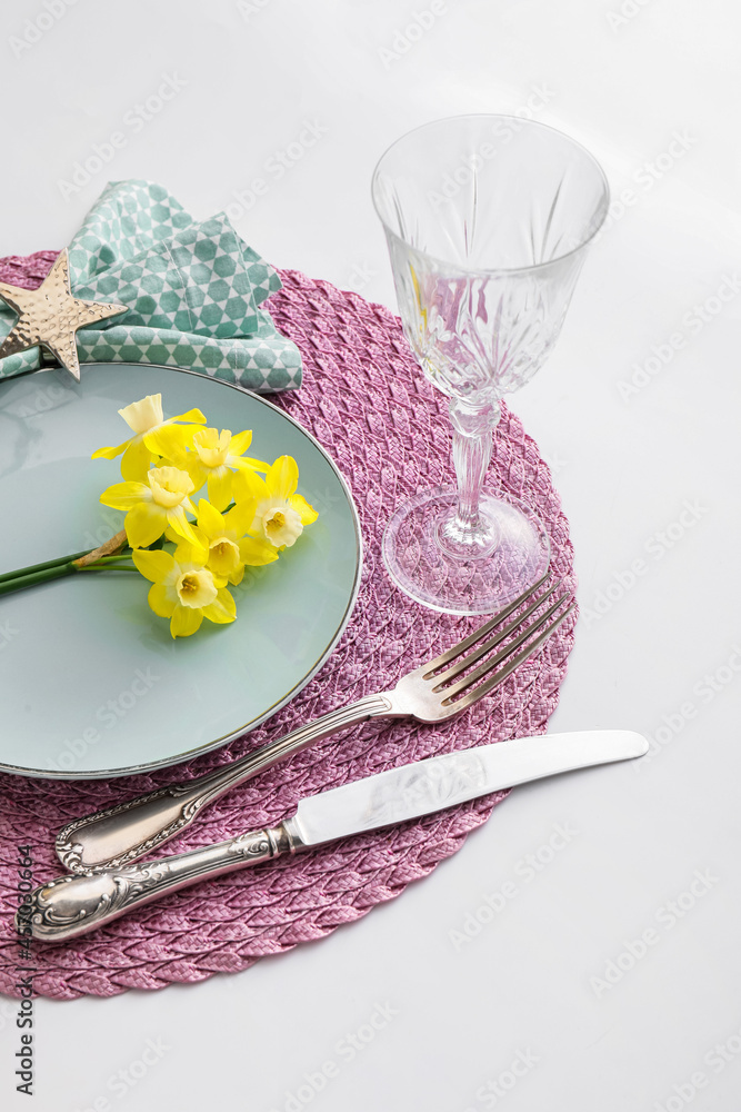 Beautiful table setting with narcissus flowers on white background Beautiful table setting with narcissus flowers on white background