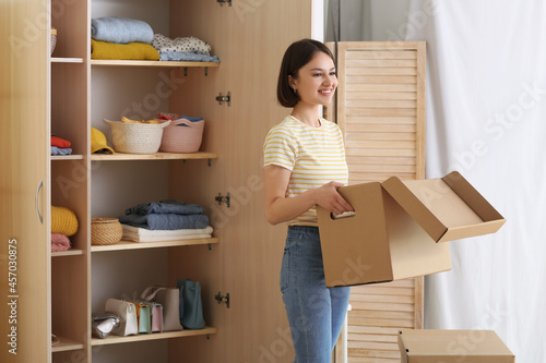 Foto Young woman organizing clothes at wardrobe