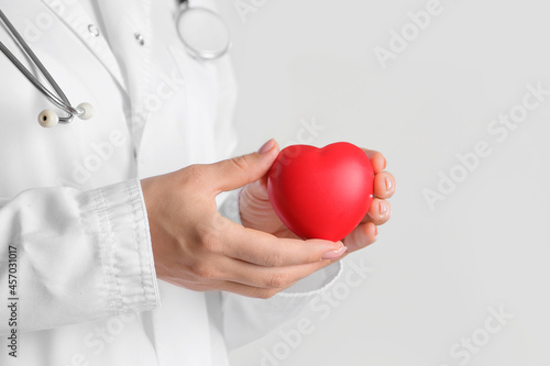 Female cardiologist with heart on light background, closeup