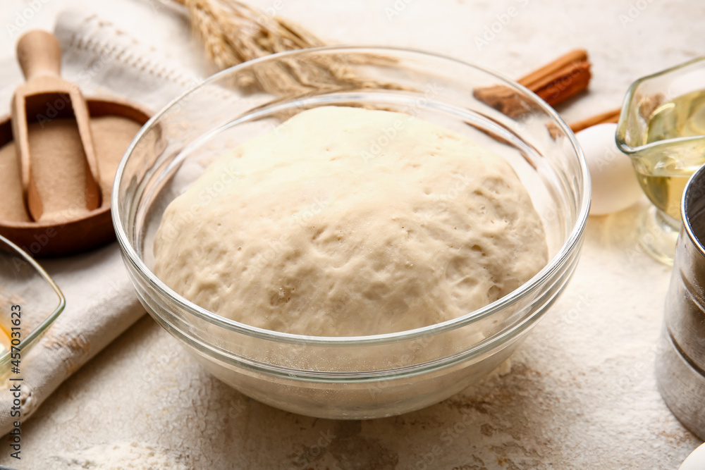 Bowl with fresh dough on light background