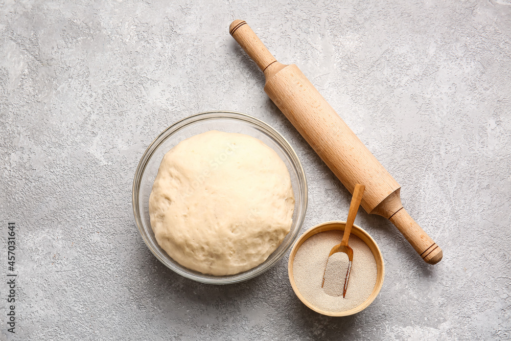 Bowl with fresh dough, dry yeast and rolling pin on light background Bowl with fresh dough, dry yeast and rolling pin on light background