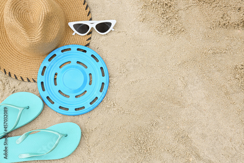 Composition with frisbee disk and beach accessories on sand