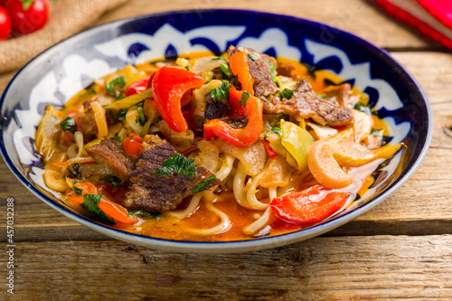 Lagman asian soup with meat and noodles on wooden table, uzbek cuisine, macro close up.