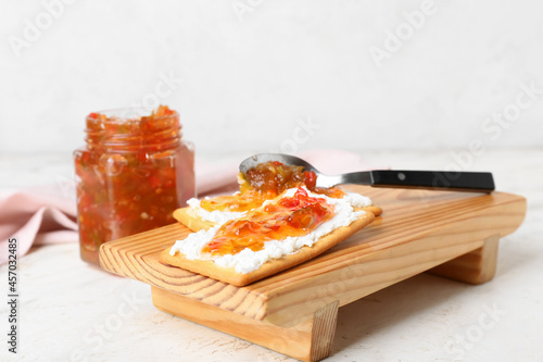 Delicious crackers with cottage cheese and jalapeno pepper jam on white table photo