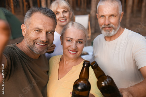 Mature people drinking beer at barbecue party outdoors