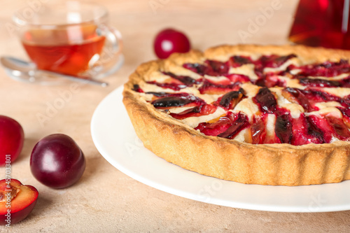 Plate with tasty plum pie on color background, closeup