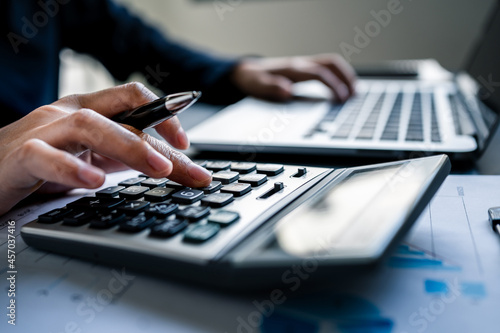Close up of businesswomen or accountant using a calculator calculates and laptop computer while working analytic business report on the workplace, Planning financial and accounting concept. photo