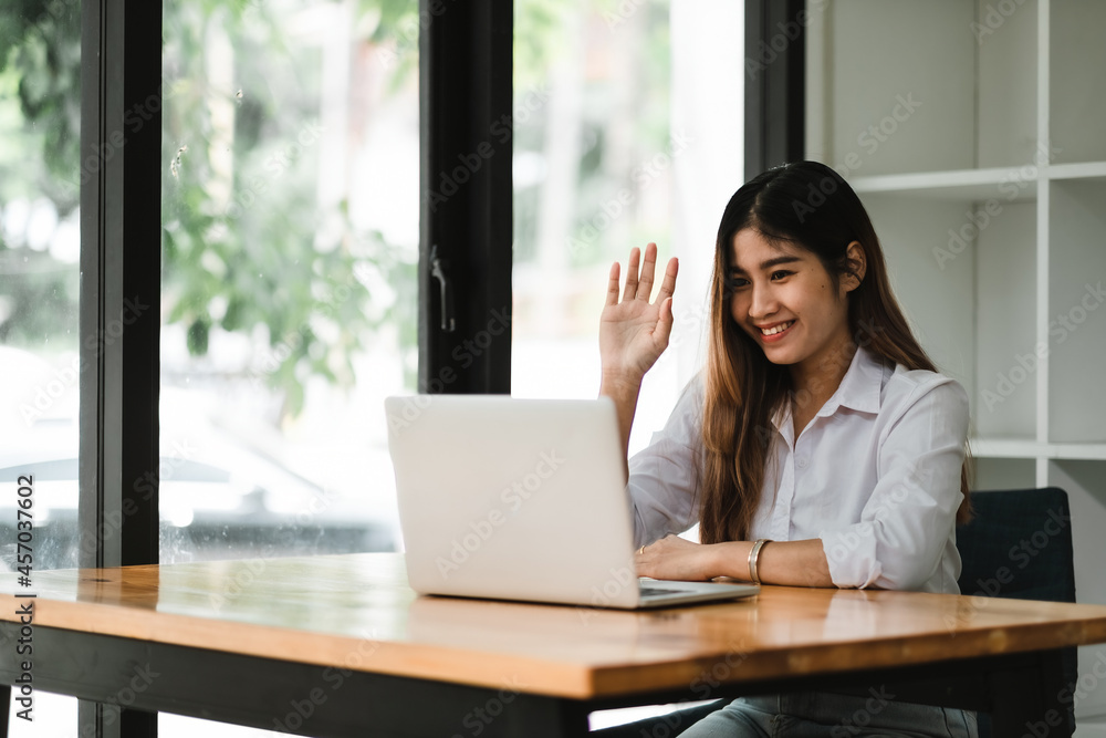 Smiling asian girl talking and waving hand hello during online video call via laptop computer, sitting in coffee shop. Cheerful business woman having conference in internet via portable notebook. Smiling asian girl talking and waving hand hello during online video call via laptop computer, sitting in coffee shop. Cheerful business woman having conference in internet via portable notebook.