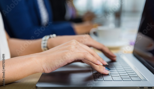 Selective focus on business woman's hands sitting and working on laptop on conference table in office. Concept for business meeting