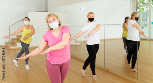 People in protective masks learning swing steps at dance class
