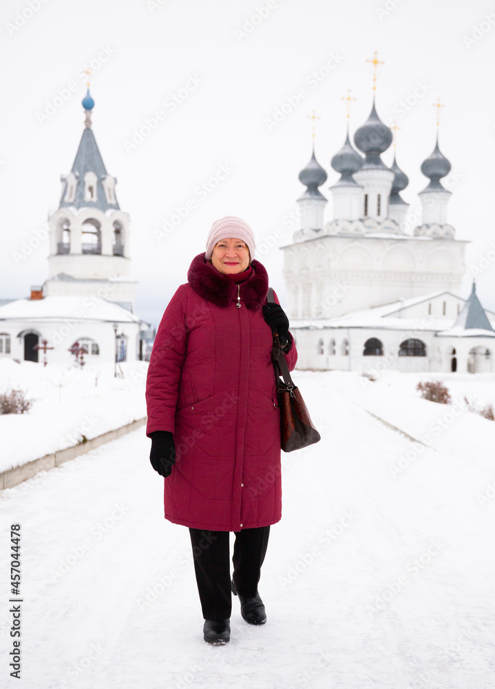 Portrait of a happy smiling woman in winter, standing against the background of the Resurrection Monastery in Murom,..Russia