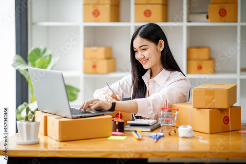 Starting Small business entrepreneur SME freelance,Portrait young woman working at home office, BOX,smartphone,laptop, online, marketing, packaging, delivery, b2b,SME, e-commerce concept