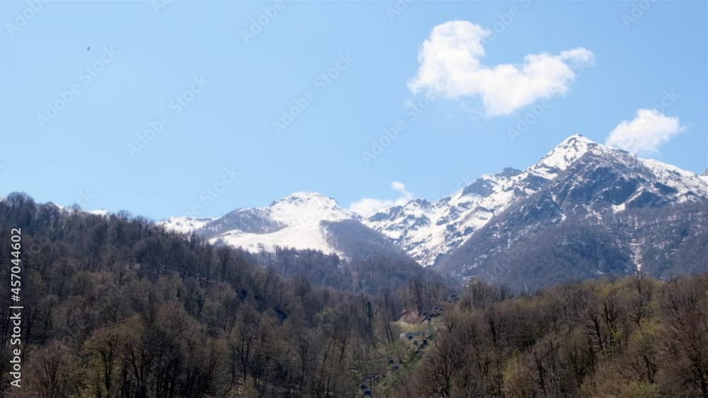 picturesque landscape of snow-capped mountains with white clouds on a blue sky on a sunny day at Krasnaya Polyana in Sochi, Russia picturesque landscape of snow-capped mountains with white clouds on a blue sky on a sunny day at Krasnaya Polyana in Sochi, Russia