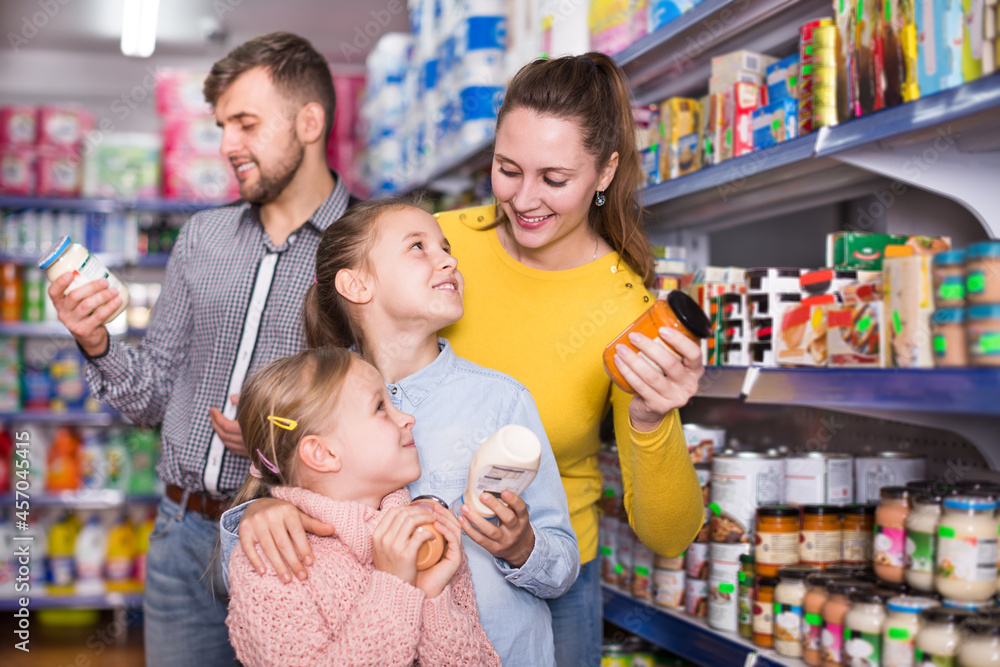 Happy parents with two daughters choosing a fresh products in food store