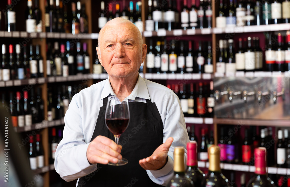 Successful elderly male owner of winery inviting to tasting wine of own production. High quality photo