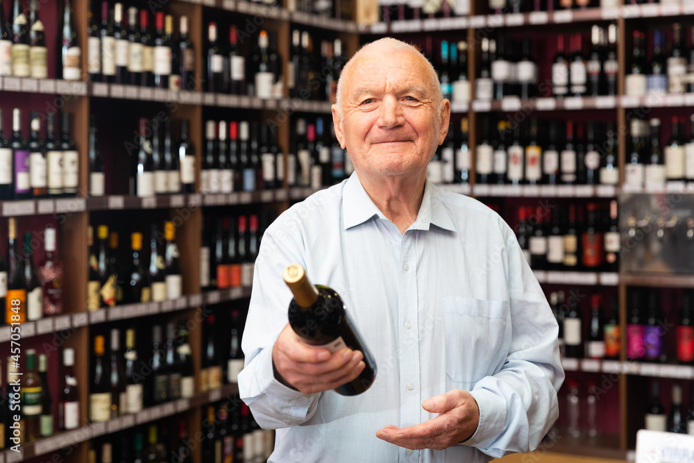 Portrait of senior man visiting winehouse in search of bottle of good wine. High quality photo