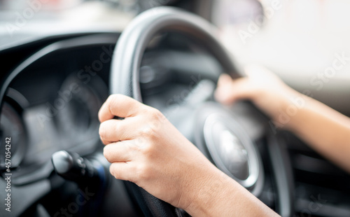 Close-up view of woman hands holding steering wheel driving a car on the city road.