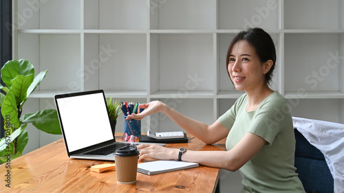 Smiling young woman designer working with laptop in creative office.