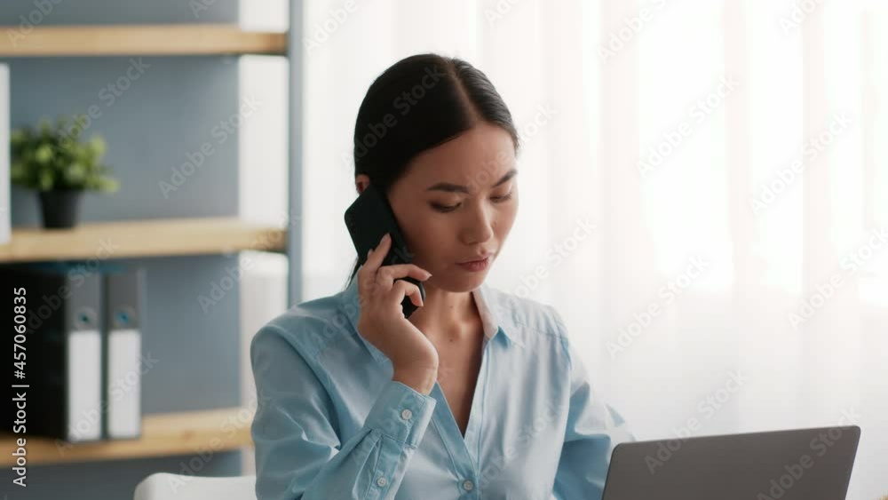 Japanese Businesswoman Talking On Phone Working On Laptop In Office Japanese Businesswoman Talking On Phone Working On Laptop In Office
