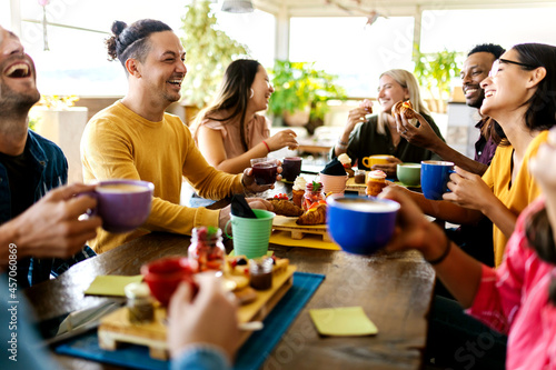 Canvas Print Smiling group of diverse friends having breakfast and talking at coffee bar rest