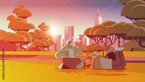 senior couple blowing bubbles and spending time with little dog in urban park relaxation retirement concept