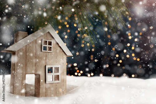 A wooden house on the window sill during snowfall - winter background