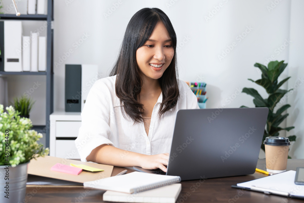 Business woman using laptop and sitting by the table in home office. Business woman using laptop and sitting by the table in home office.