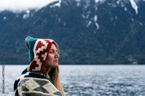 Portrait of a young woman with a relaxed expression wearing a colorful poncho in the rain on her trip to Peulla.