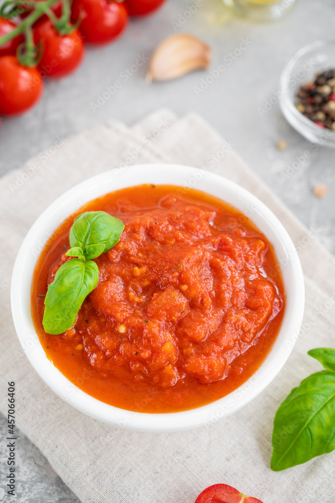 Traditional Italian marinara sauce in a bowl on a concrete background with spices and ingredients. Top view. Copy space. Traditional Italian marinara sauce in a bowl on a concrete background with spices and ingredients. Top view. Copy space.