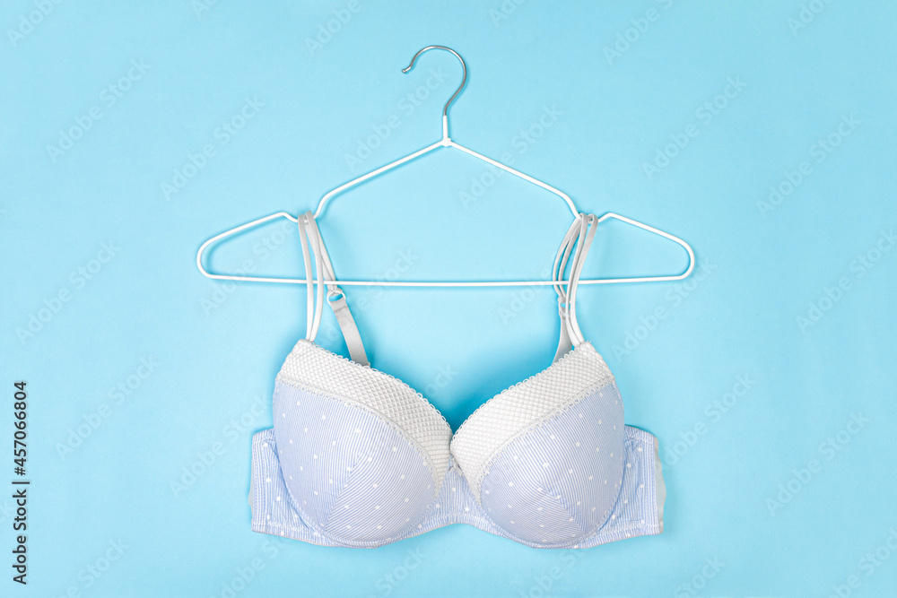 Top view of stylish women bra on white hanger on light blue background with copy space. Women's wardrobe Top view of stylish women bra on white hanger on light blue background with copy space. Women's wardrobe