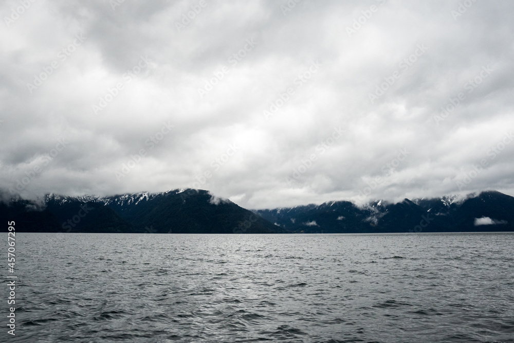 Panoramic view of snow-capped mountains on a cloudy day and a lake on the bottom
