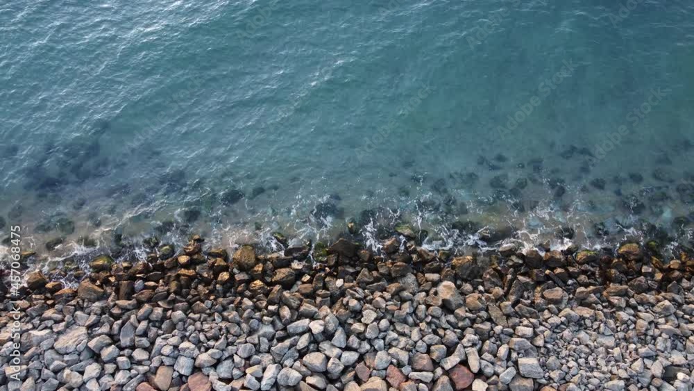 Shore with stones washing the waves of the blue sea Shore with stones washing the waves of the blue sea