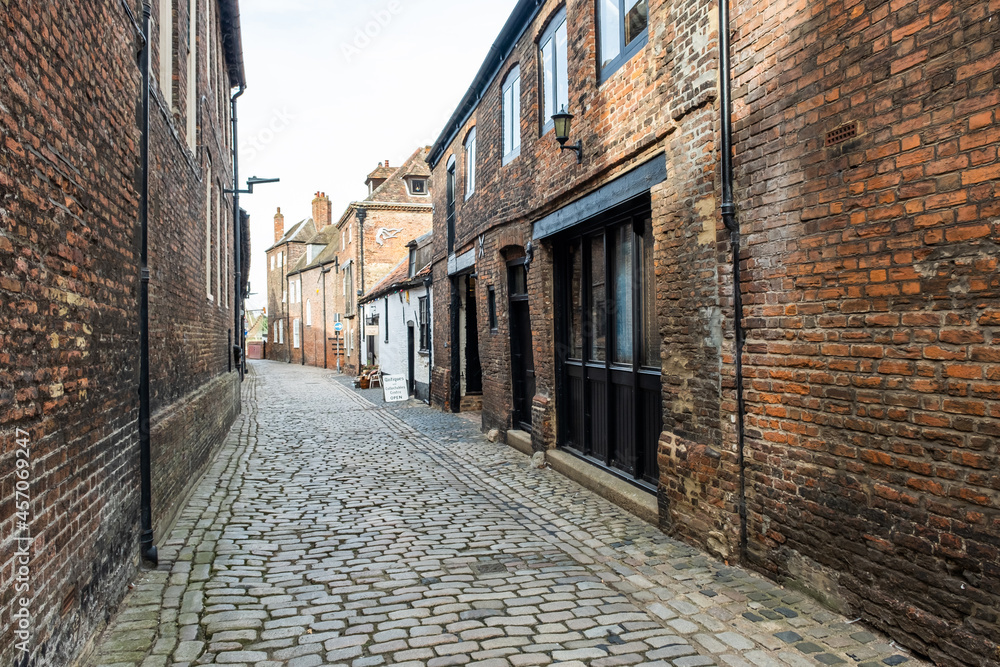 Narrow alley way with historic brick buildings and a cobbled street