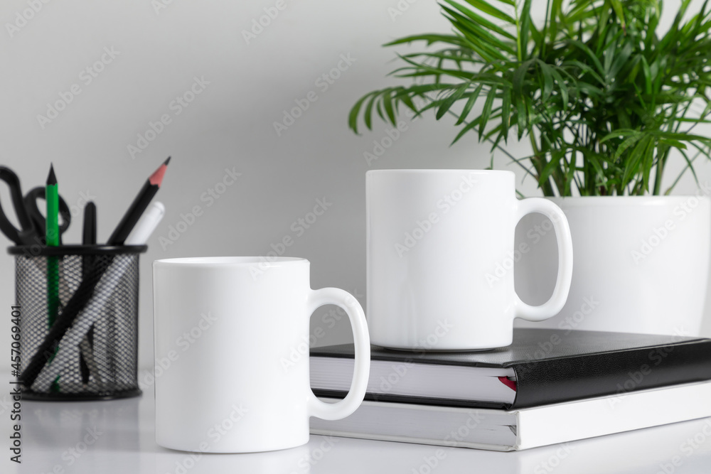 Two mugs mockup with accessories on white table. front view Two mugs mockup with accessories on white table. front view