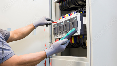 Electrical engineer tests the operation of the electric control cabinet on a regular basis for maintenance.