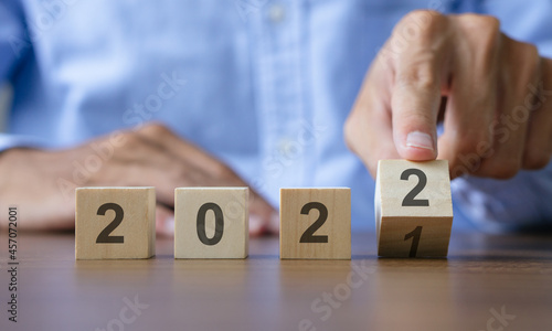 Man hand flipping of wooden cubes block to change 2021 to 2022 year. Merry Christmas and happy new year concept.