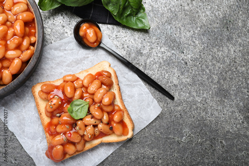 Toast with delicious canned beans on grey table, flat lay. Space for text