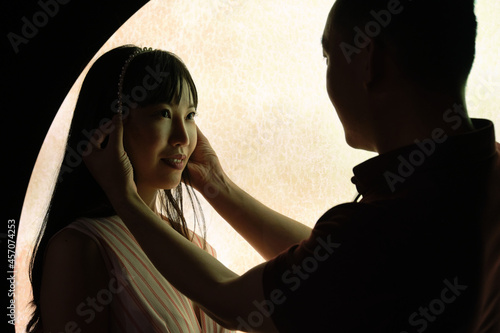 Young asian man put a crown on his girlfriend head over a moon background.