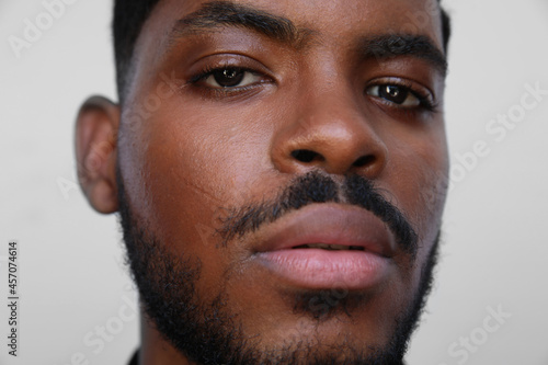Close-up of handsome young black man looking a side on white background.
