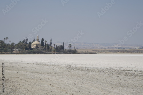 Larnaca, Cyprus, September 2021: Hala Sultan Tekke Mosque on the background of a salt lake. Dried up salt lake. Natural salt on the surface of the earth