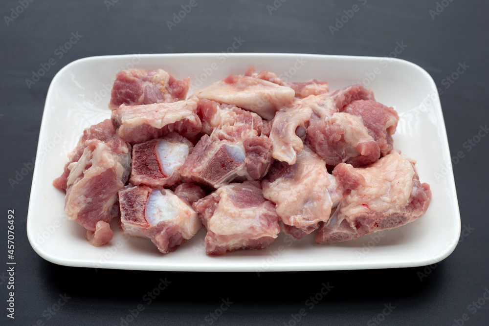 Raw pork ribs in white plate on dark background. Raw pork ribs in white plate on dark background.