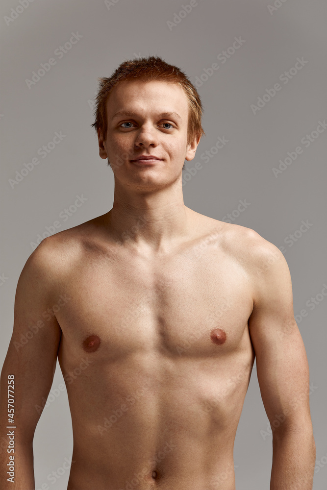 Fototapeta premium Young swimmer in excellent physical shape, on a gray background with copy space, call for sports, advertising banner